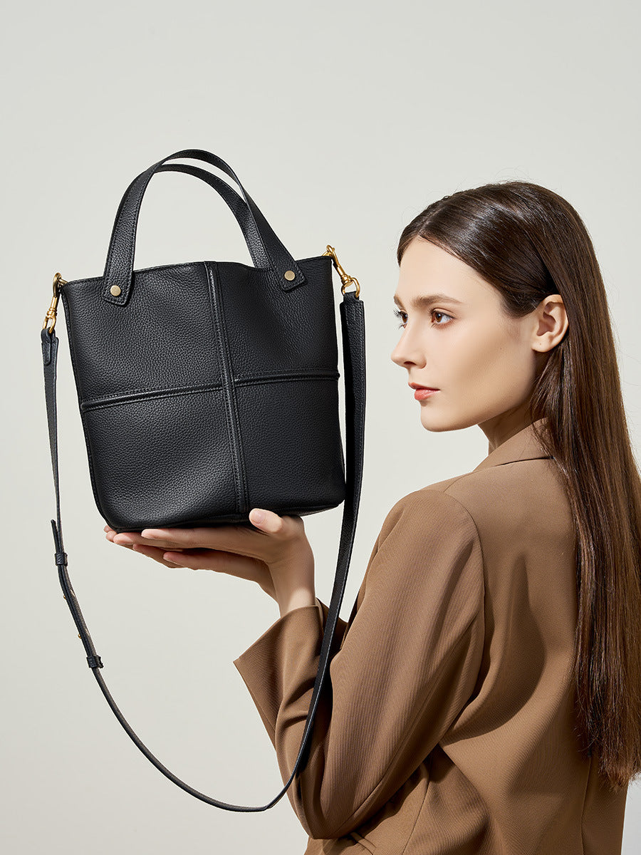 Model holding black bucket bag with detachable strap