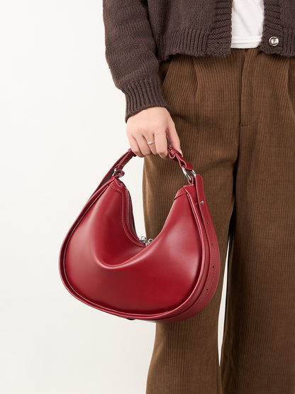 Model carrying burgundy leather crescent bag by top handle