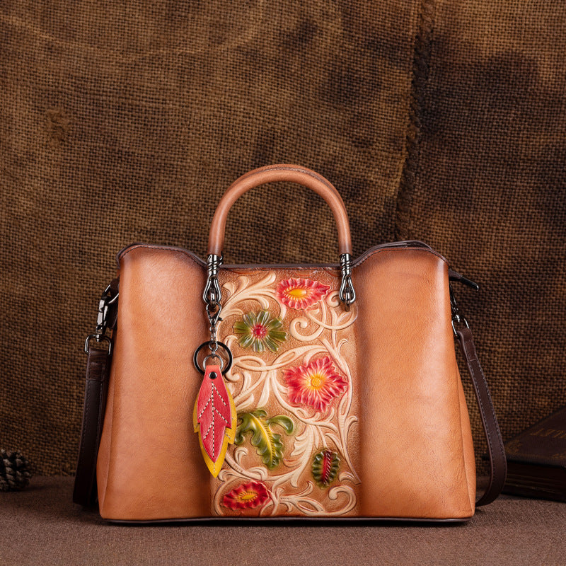 Brown cowhide handbag with embossed floral front panel and top handle