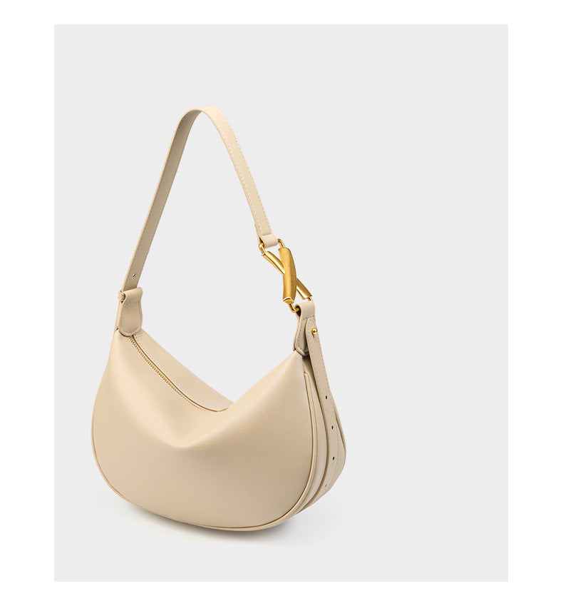 Three-quarter view of off-white cowhide crescent underarm bag with strap detail