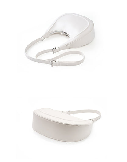 Cream white crescent bag shown flat with the extender crossbody strap