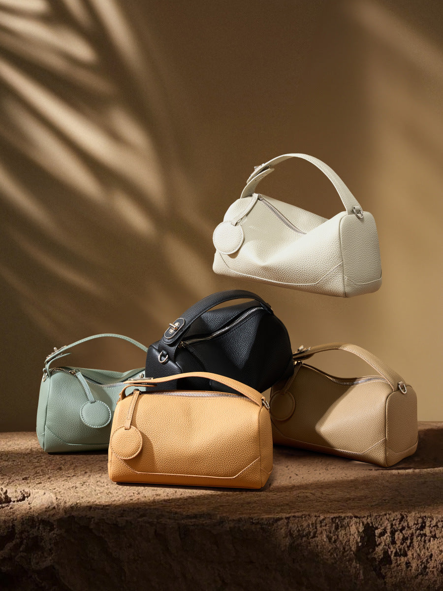 Group of five mini Boston bags in different colorways arranged on stone