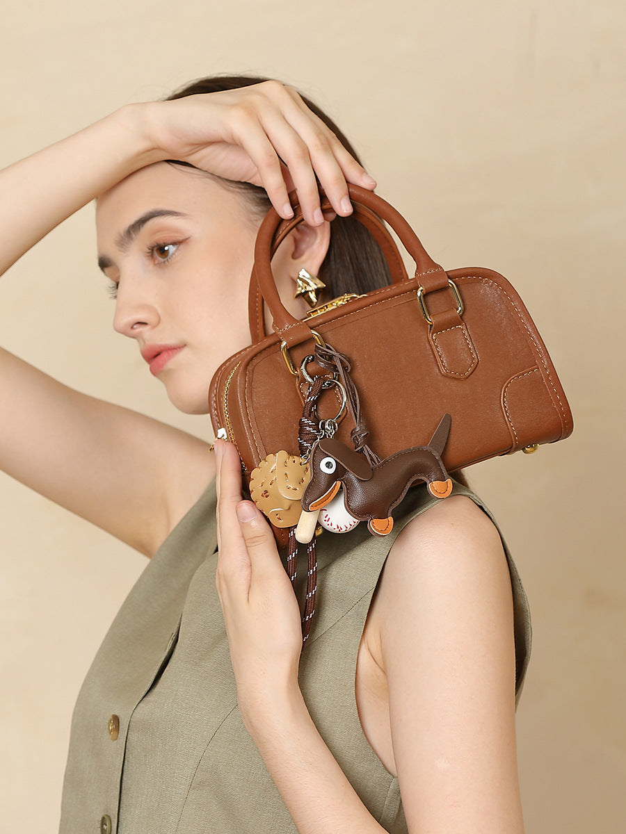 Model holding brown mini bowling bag by the top handle