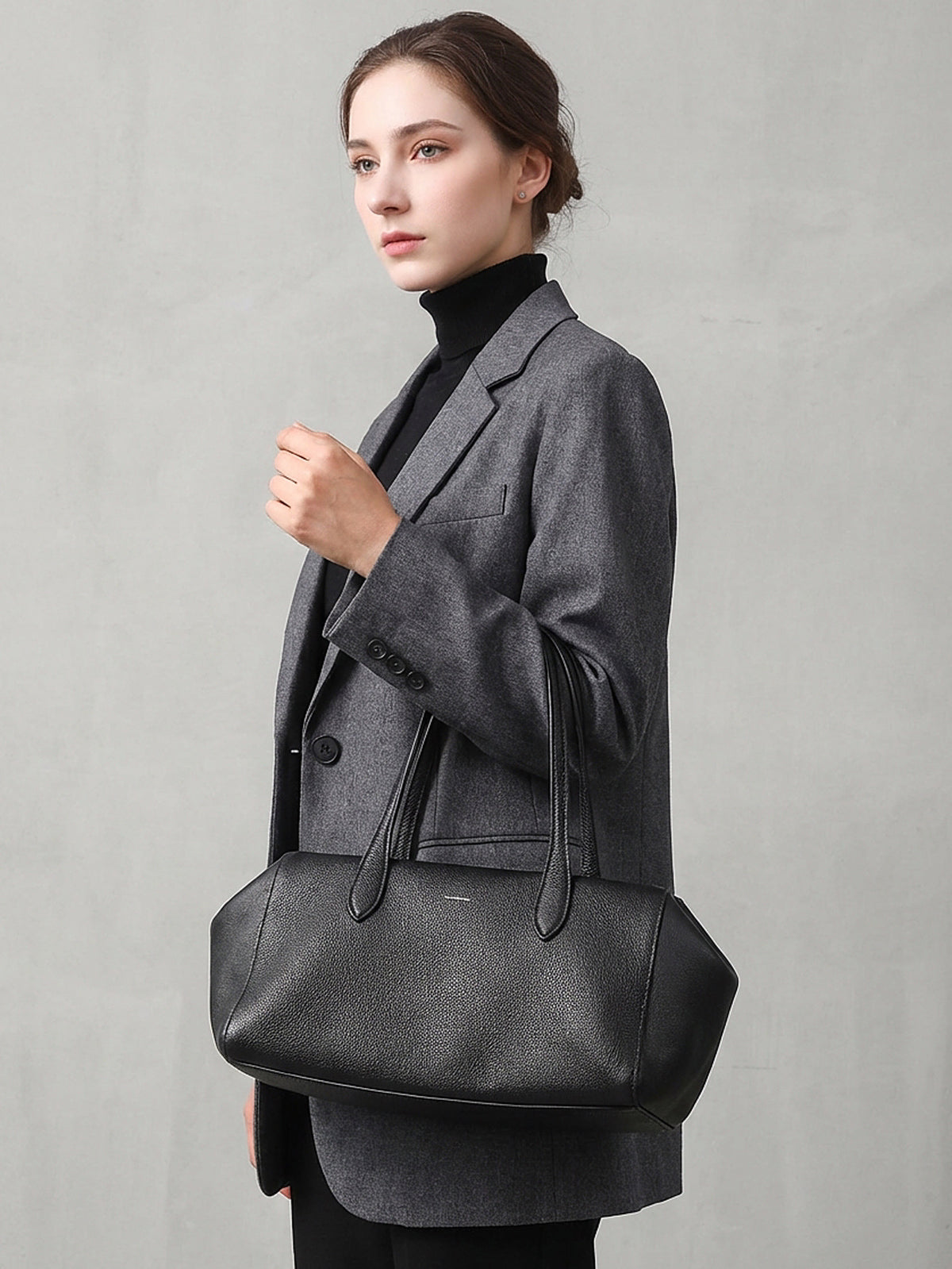Model carrying the black leather tote over one shoulder