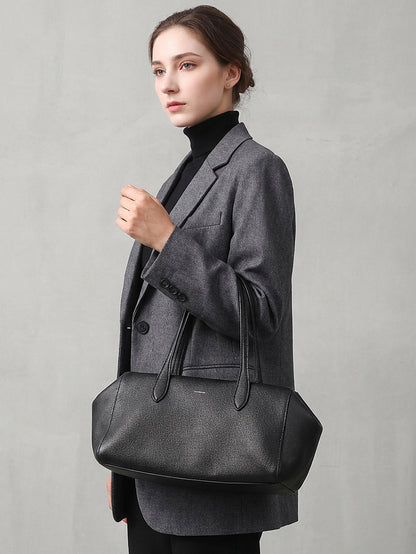 Model carrying the black leather tote over one shoulder