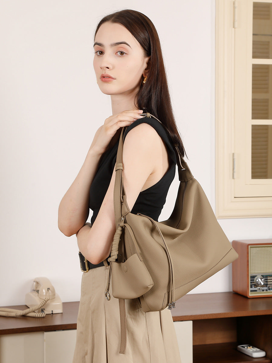 Model carrying gray cowhide leather hobo bag on the shoulder