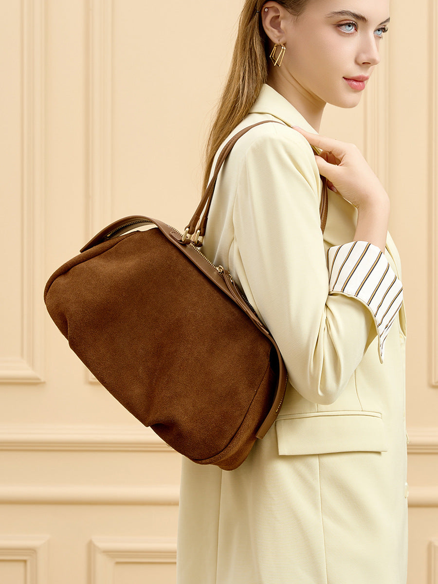 Brown leather shoulder bag carried by hand