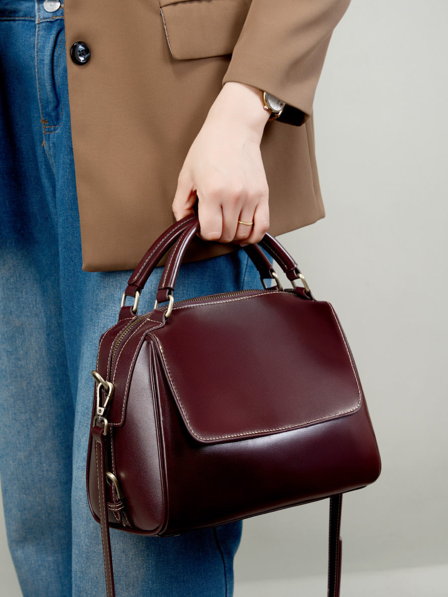 Wine brown leather Boston bag carried by top handle with model in jeans and blazer
