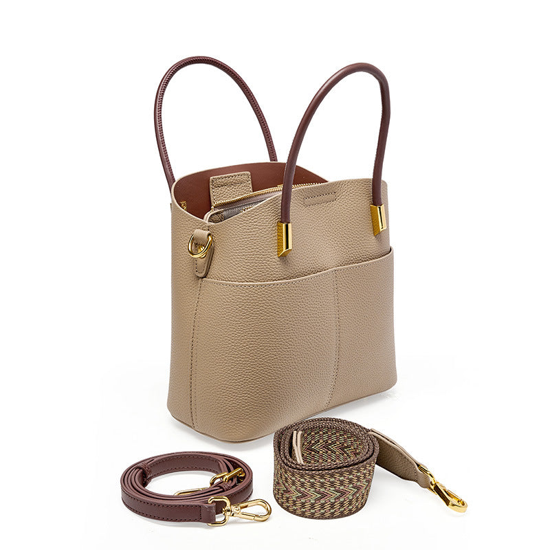 Gray bucket bag with leather and woven shoulder straps displayed beside it