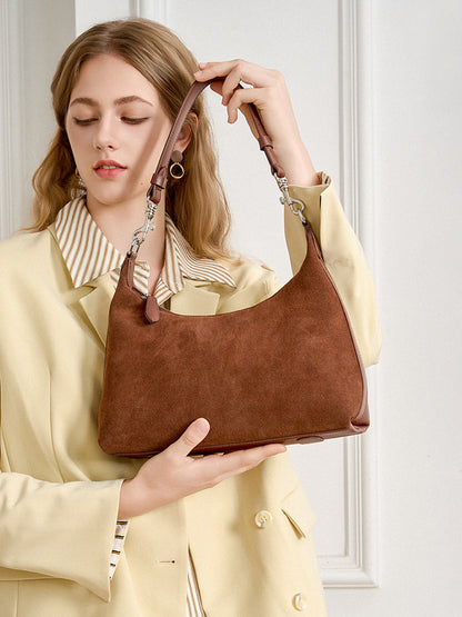 Model holding the brown shoulder bag by its adjustable strap
