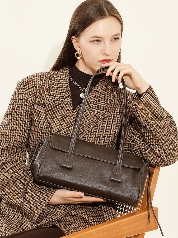 Model in houndstooth coat holding dark brown cowhide leather shoulder bag