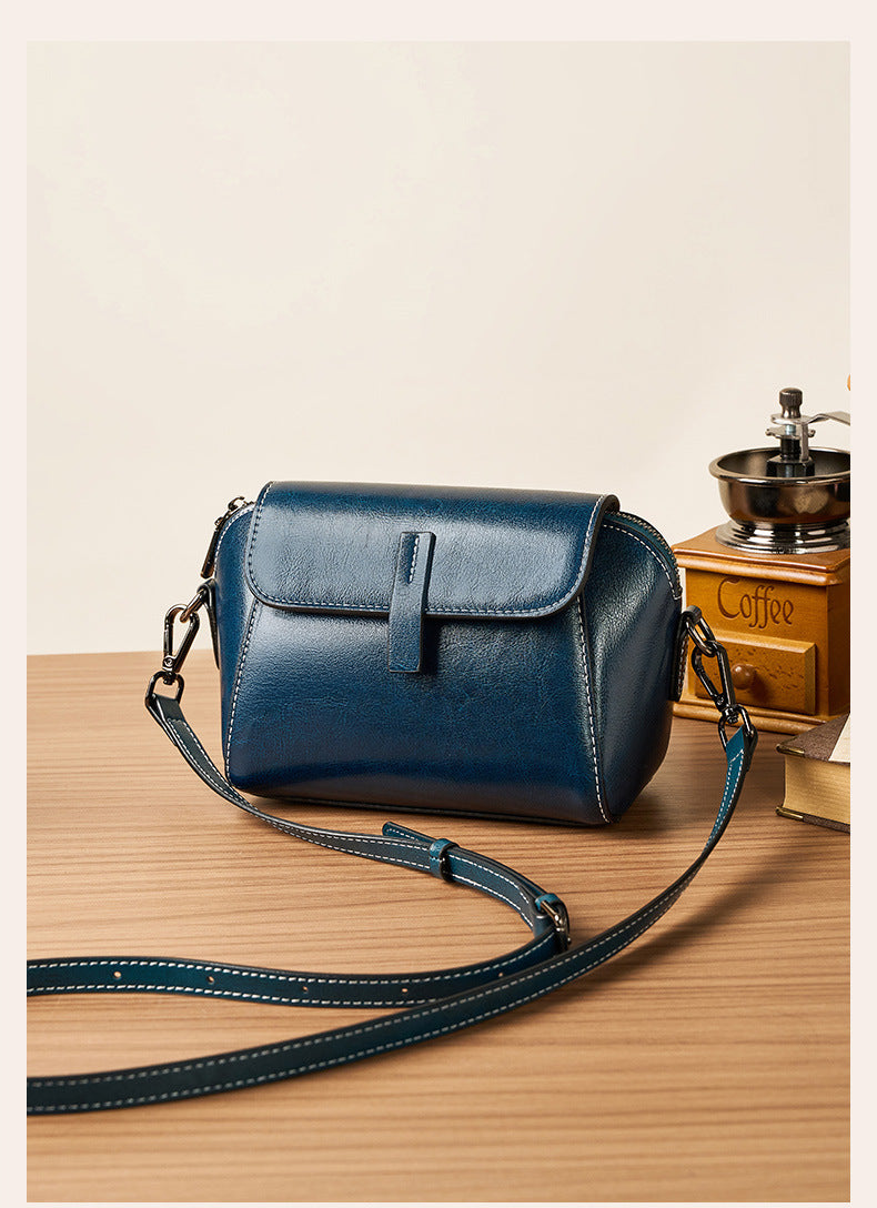 Peacock blue crossbody bag styled with vintage coffee grinder on wooden table