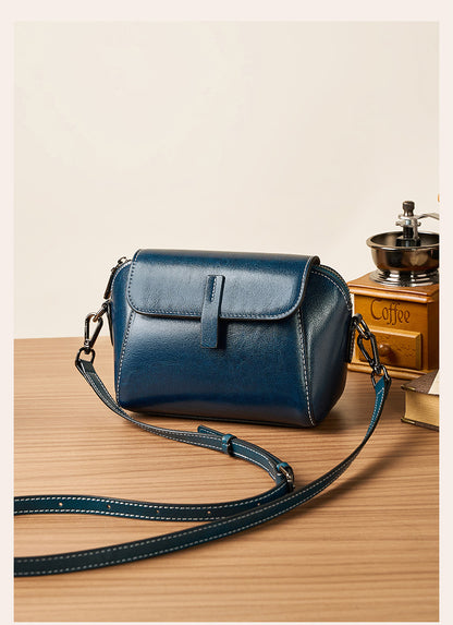 Peacock blue crossbody bag styled with vintage coffee grinder on wooden table