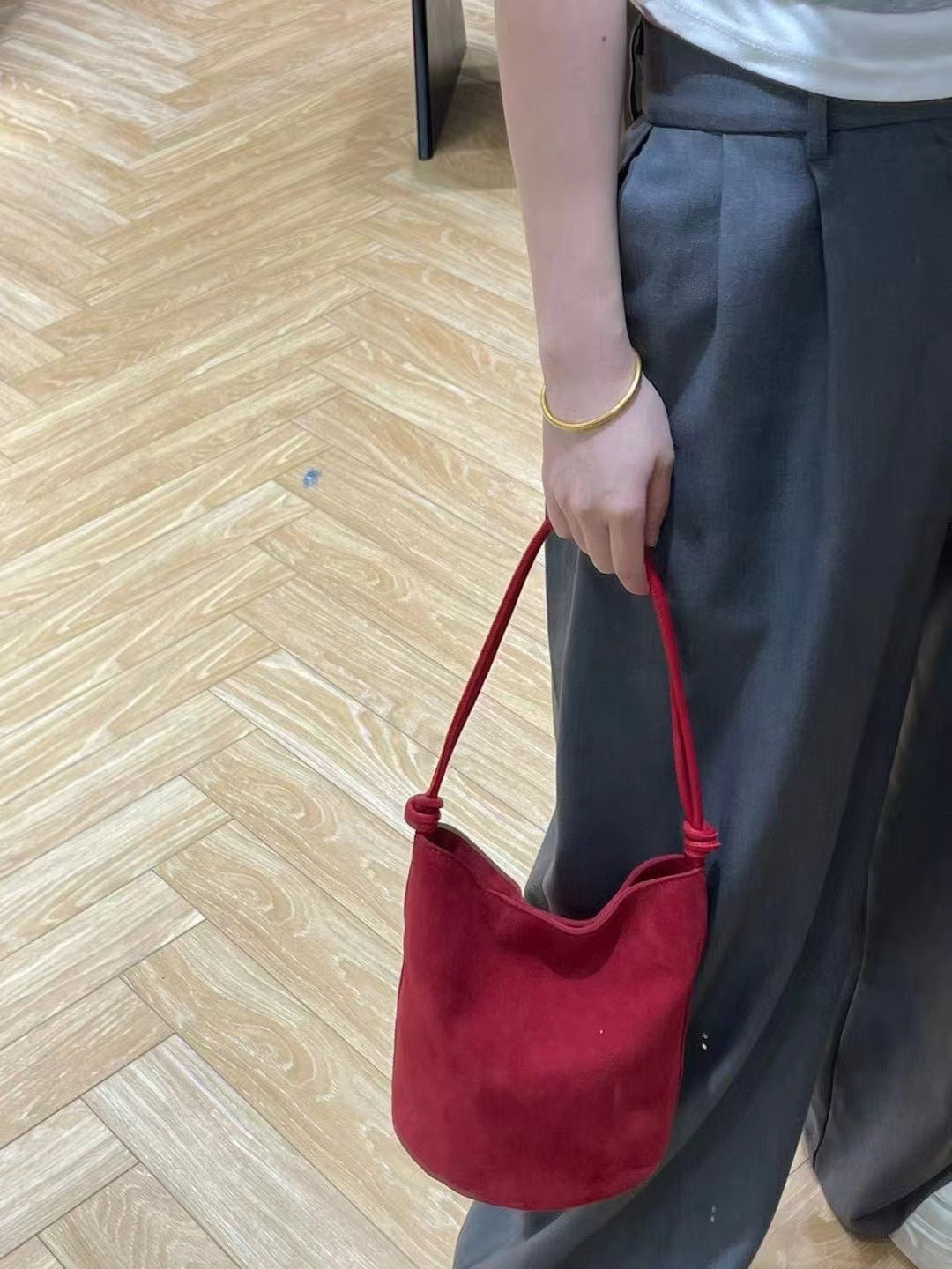 Red bucket bag carried by hand at the strap