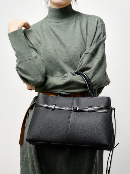 Model in green sweater holding black pebbled leather tote
