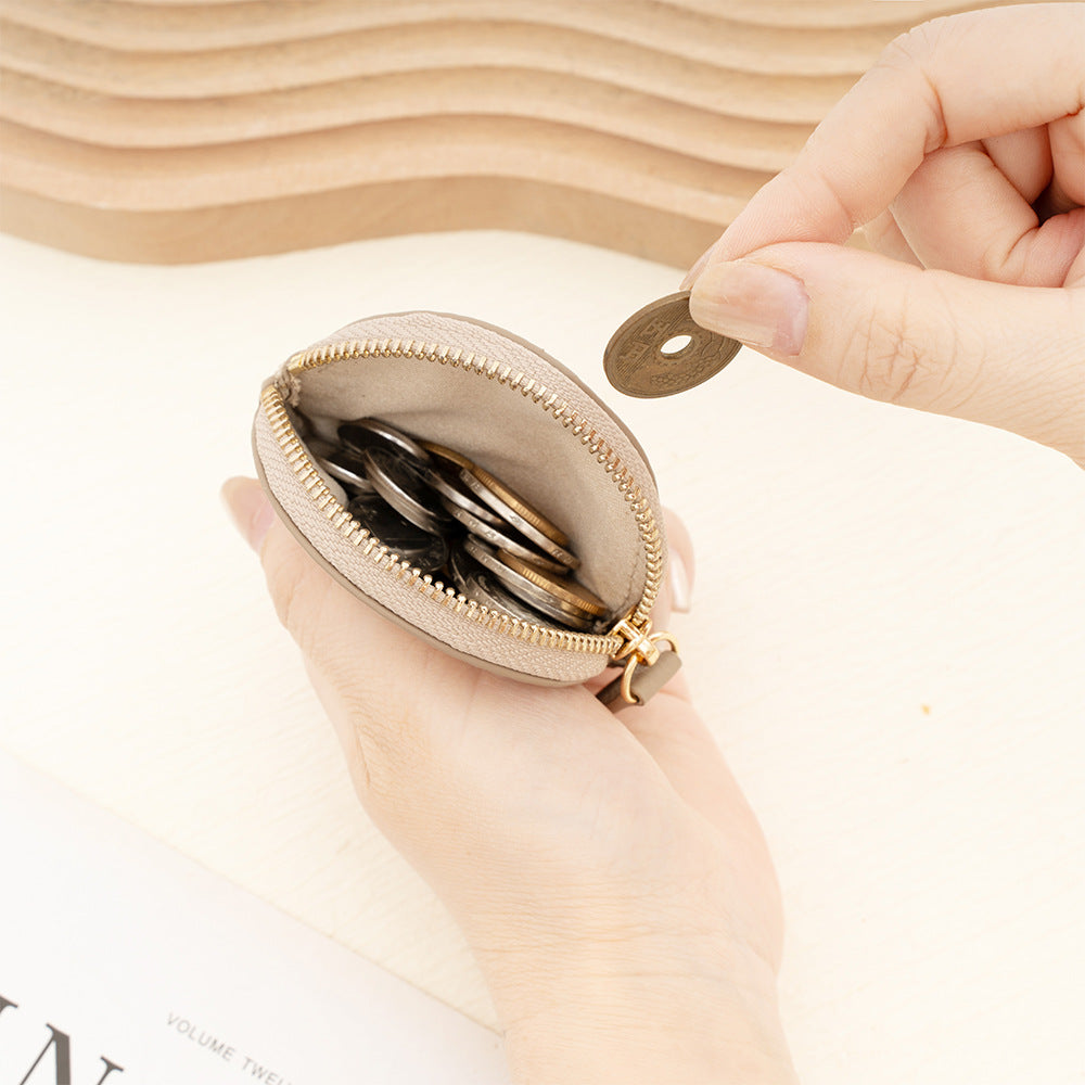 Hand holding open round leather coin purse filled with coins
