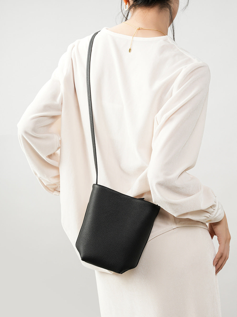 Model carrying black mini bucket crossbody bag from behind
