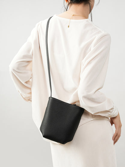Model carrying black mini bucket crossbody bag from behind