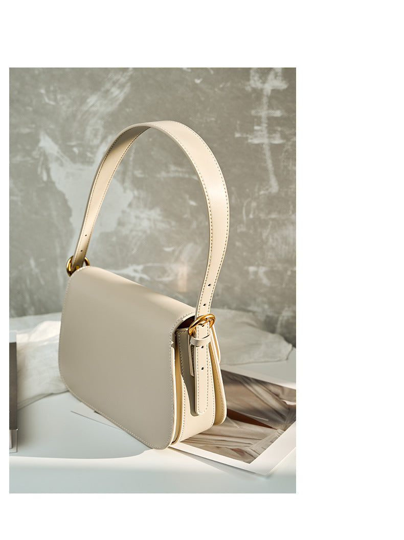 Side profile of off-white leather shoulder bag showing strap attachment and side pocket