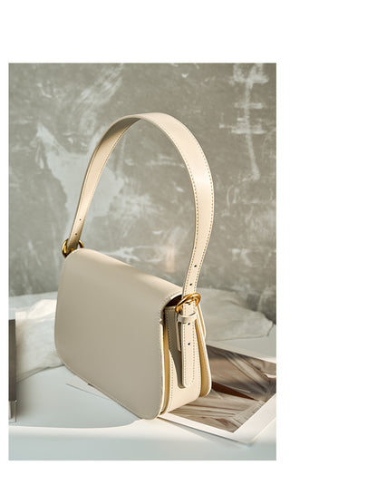 Side profile of off-white leather shoulder bag showing strap attachment and side pocket
