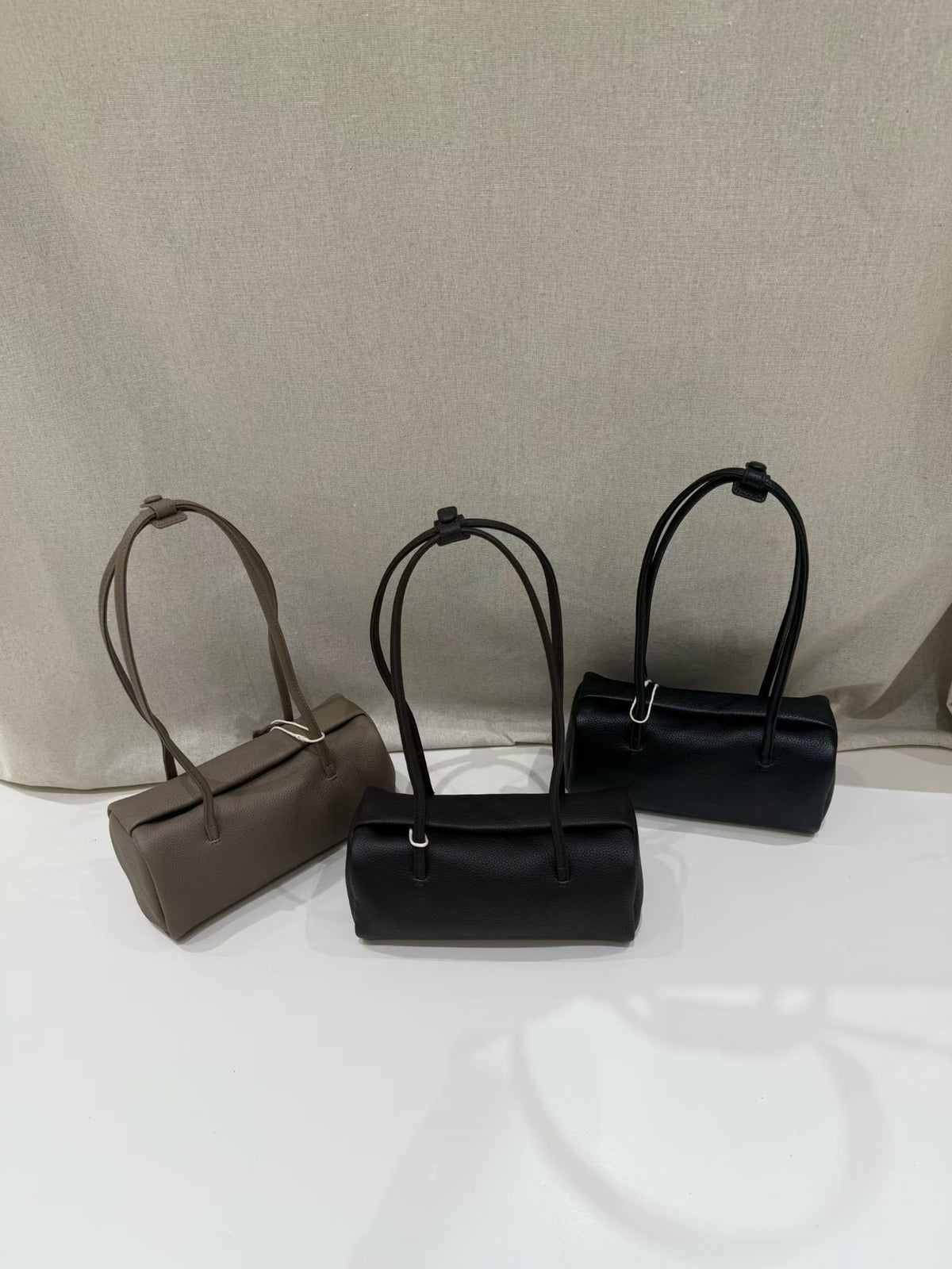 Three pillow-shaped shoulder bags arranged side by side