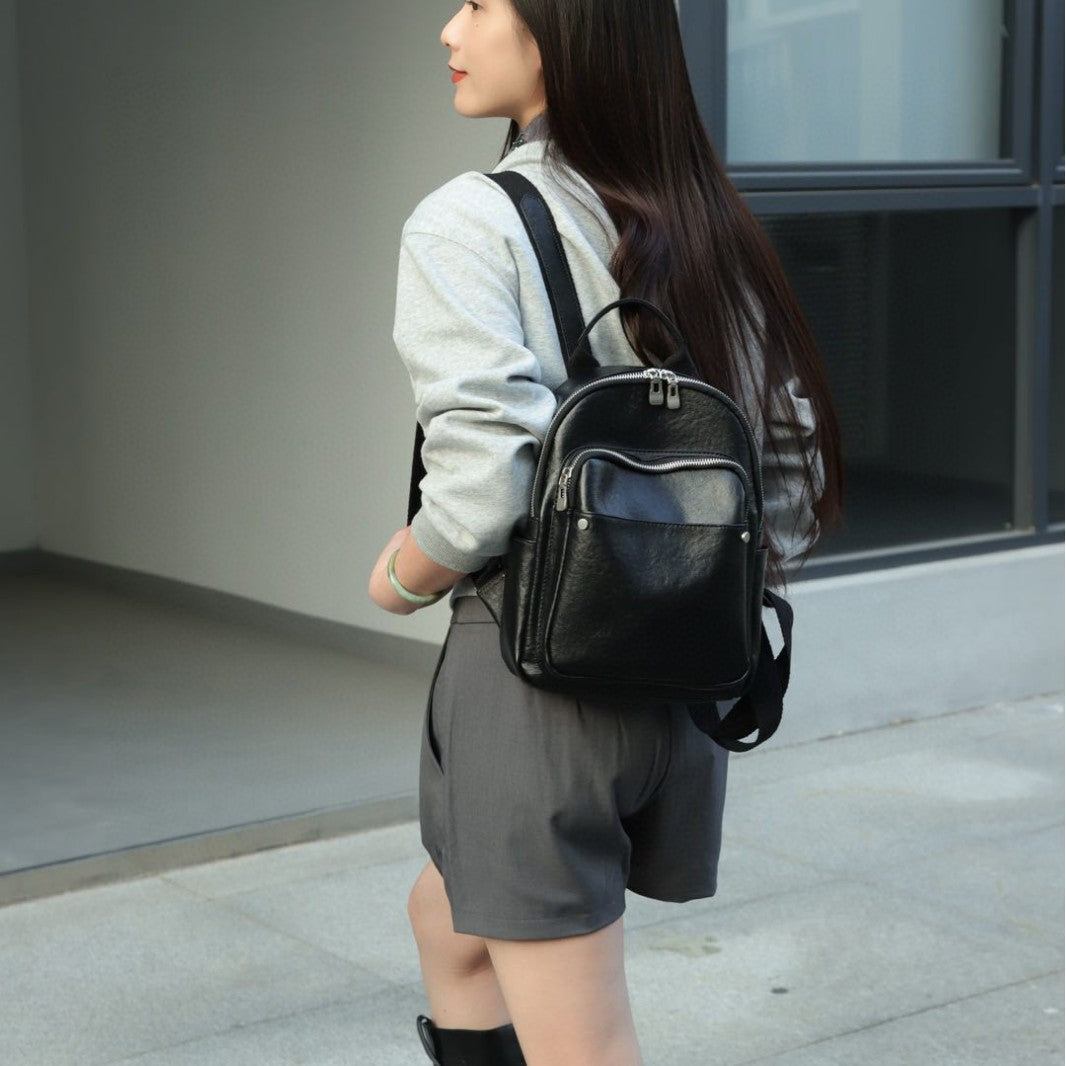 Black cowhide backpack worn over one shoulder