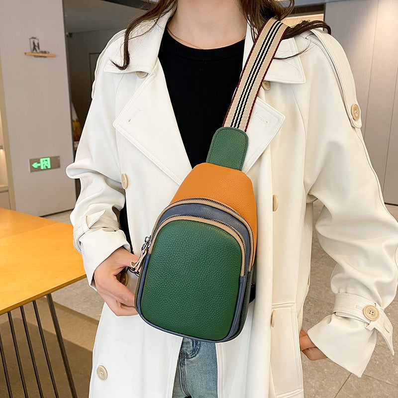 Green and orange sling bag styled over a light coat