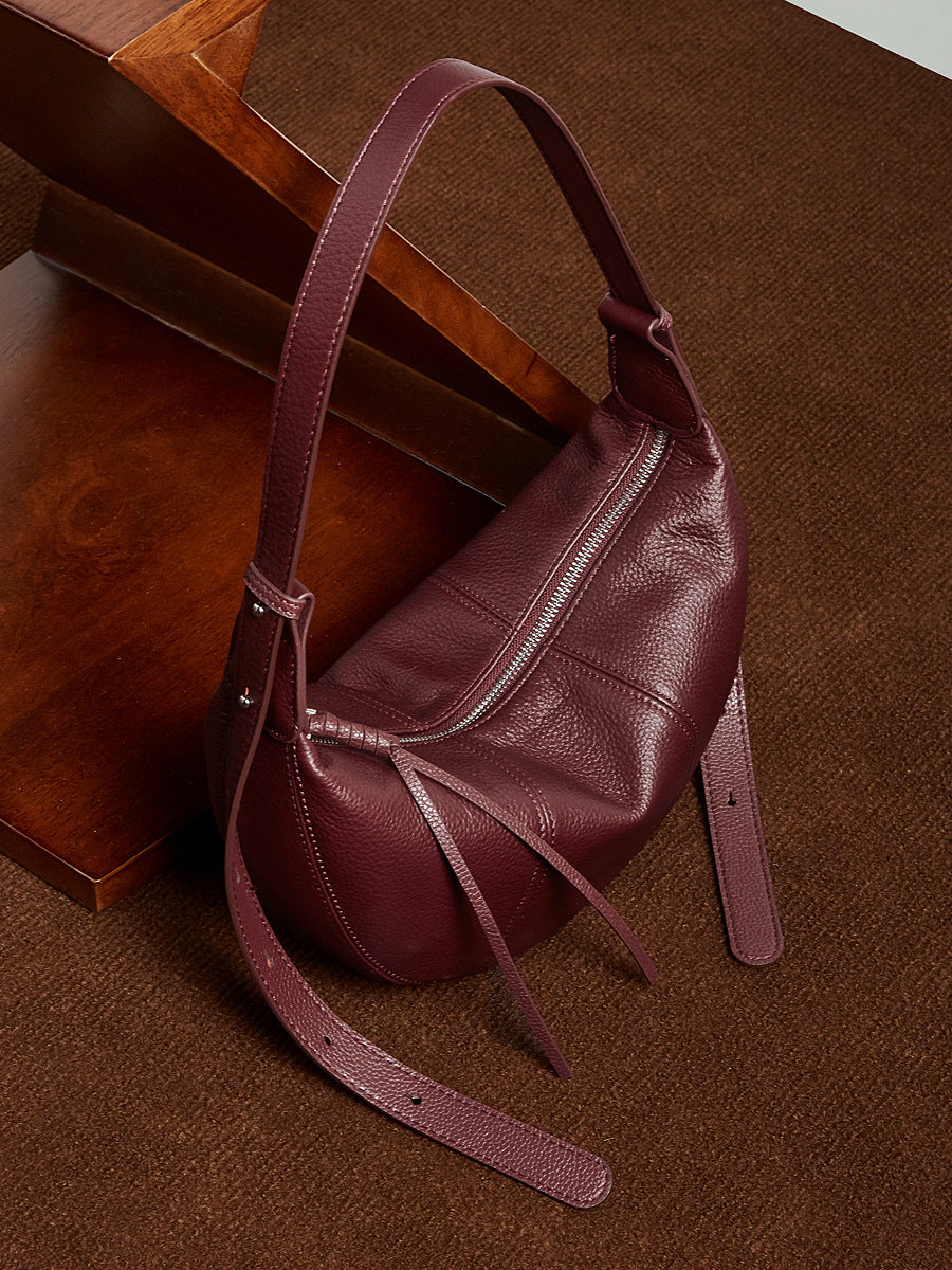 Wine red hobo bag resting on wooden surface showing top zipper