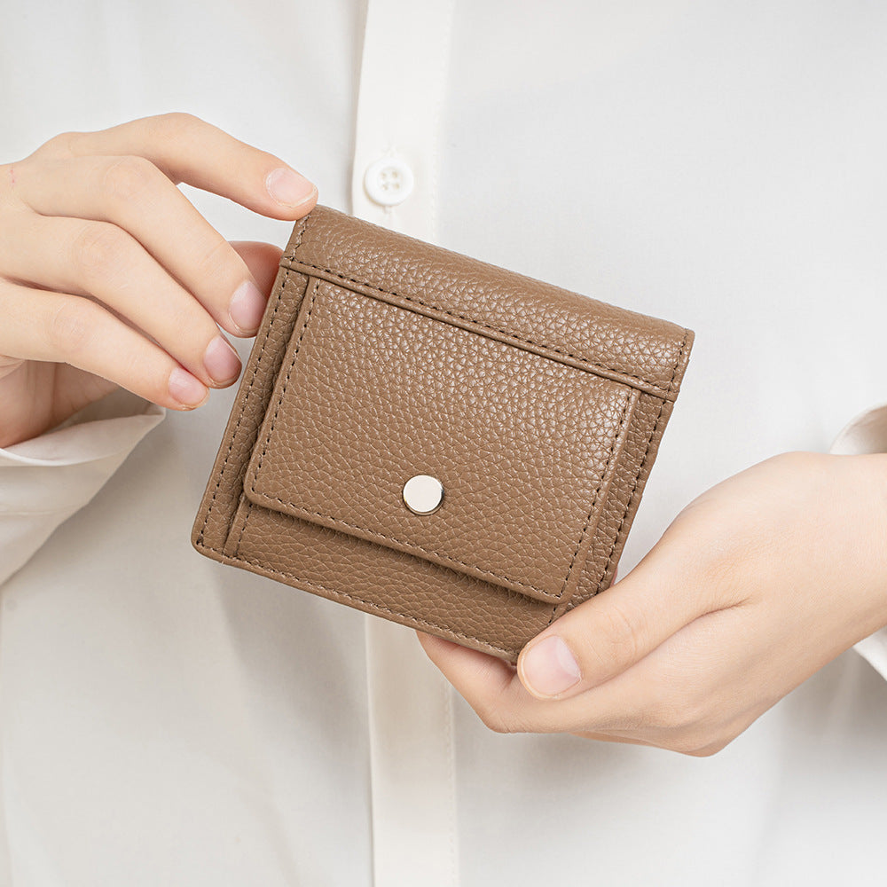 Brown folding wallet held in hands for scale