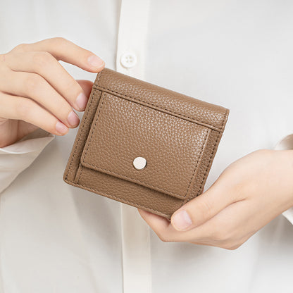 Brown folding wallet held in hands for scale