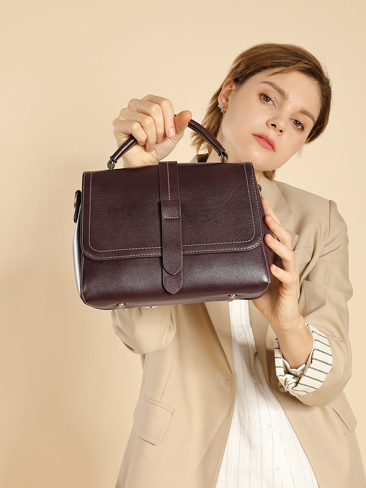 Model holding the wine brown leather Boston bag by its top handle