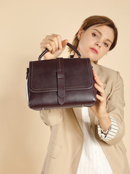 Model holding the wine brown leather Boston bag by its top handle