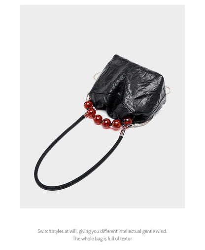 Black crinkle bag laid flat showing bead handle and chain strap detail