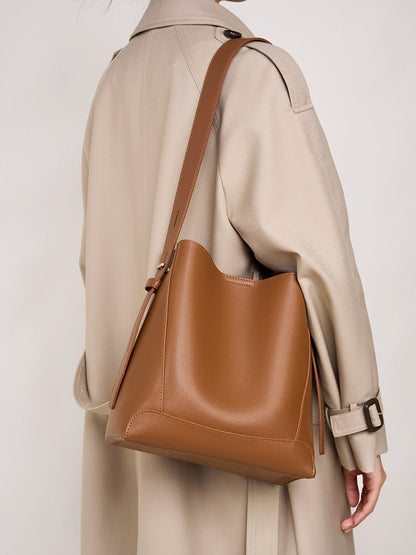 Model wearing Golden Brown bucket bag with trench coat