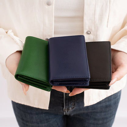 Person holding three slim genuine leather card holder wallets in green, navy blue, and black colors
