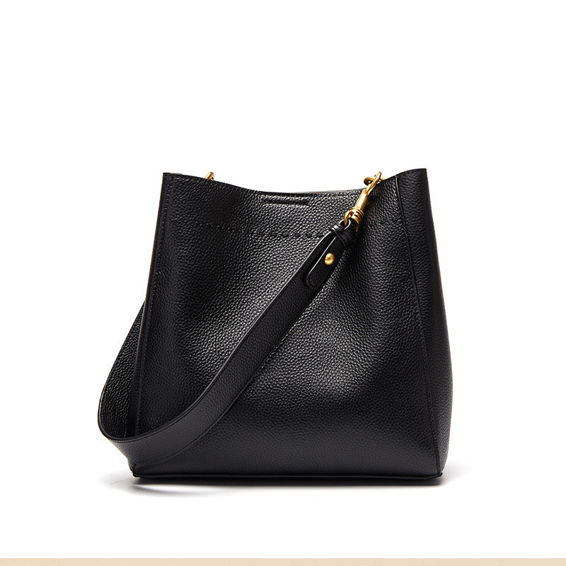 Black cowhide leather bucket tote bag on white background with adjustable strap