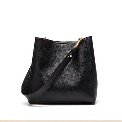 Black cowhide leather bucket tote bag on white background with adjustable strap