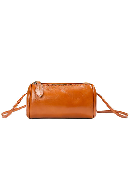Caramel brown leather barrel bag on table with magazine
