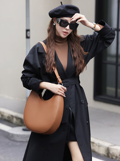 Model wearing brown crescent hobo bag with black trench coat and beret
