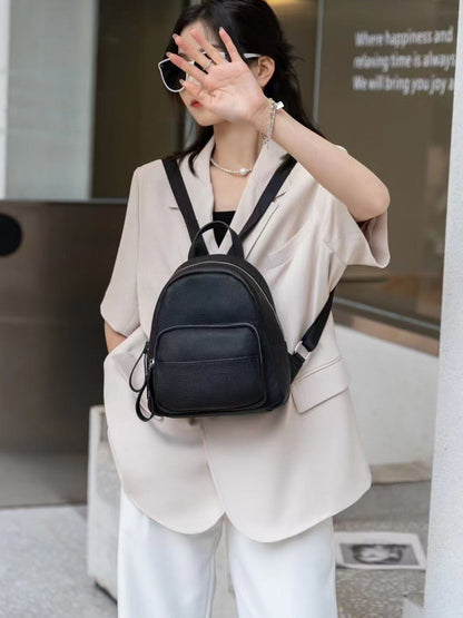 Ivory backpack worn over the shoulder with straps visible