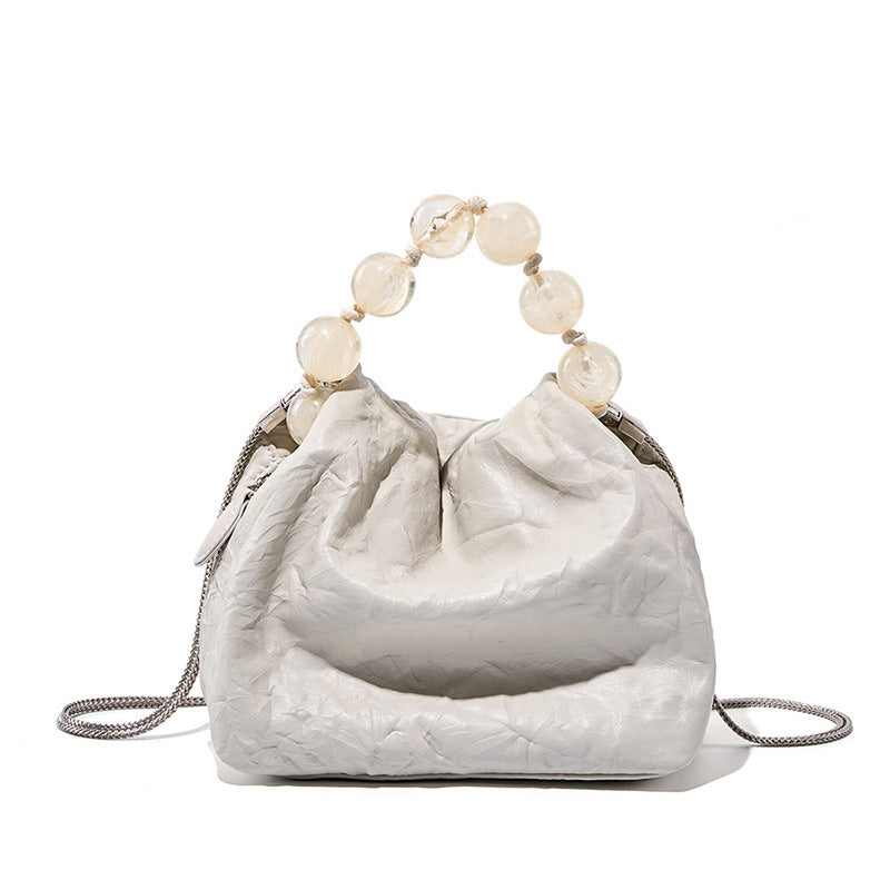 Off-white crinkle cowhide crossbody bag with pearl bead handle on white background