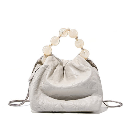 Off-white crinkle cowhide crossbody bag with pearl bead handle on white background
