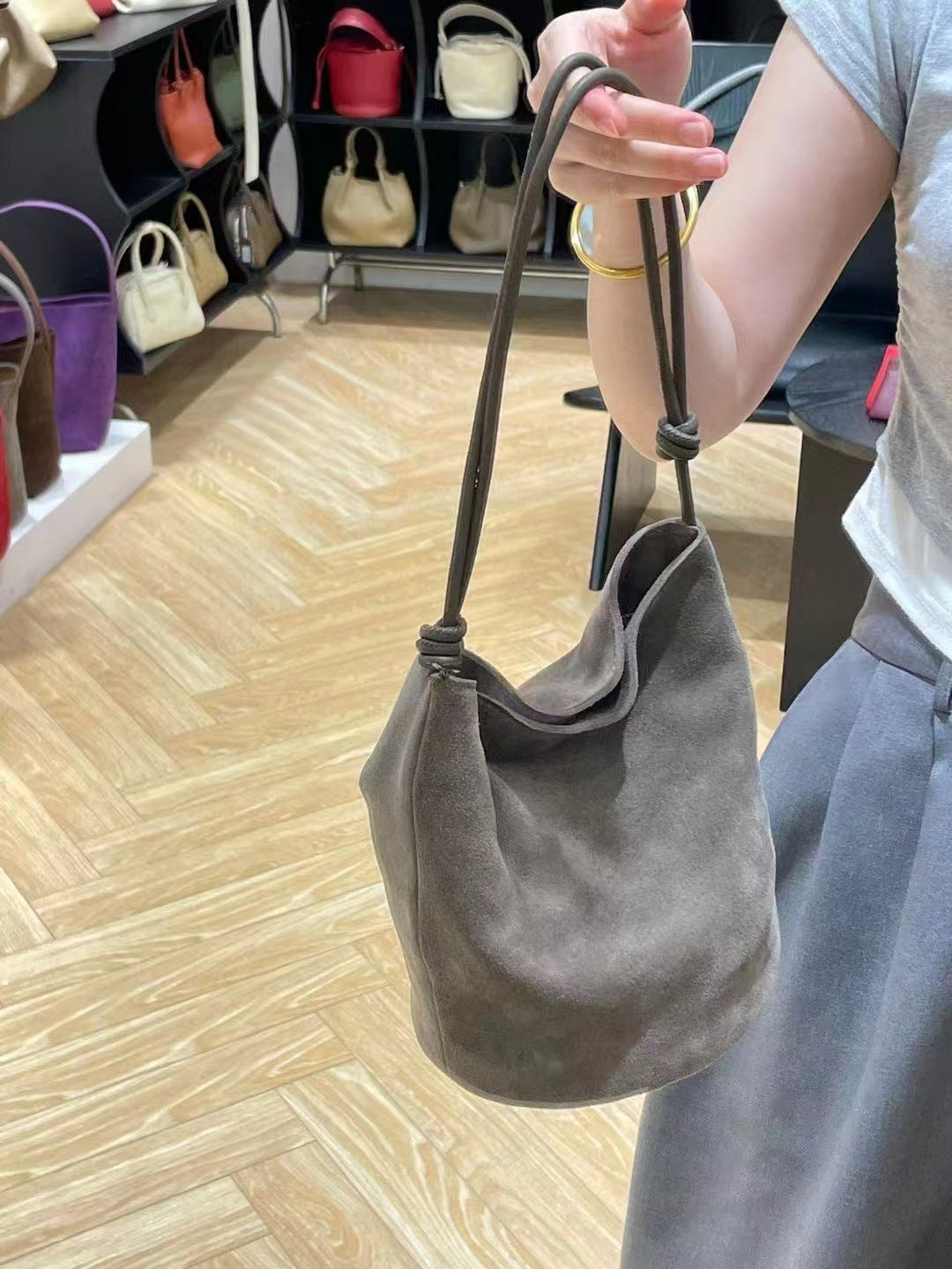 Gray bag held by its strap, showing the soft bucket shape