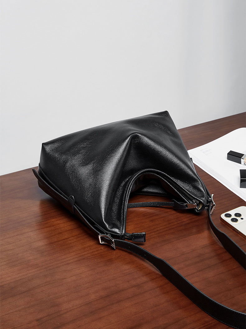 Black leather bag lying flat on a wooden surface