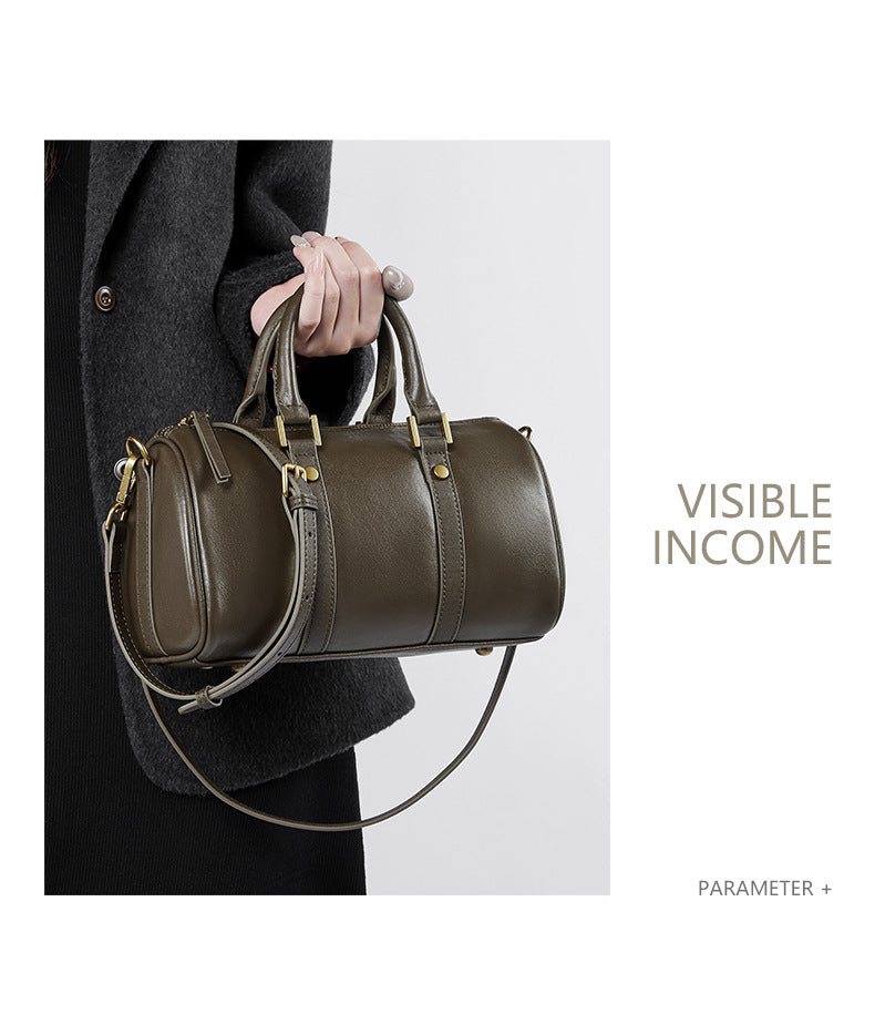 Olive green Boston bag held by top handle with visible gold-tone hardware