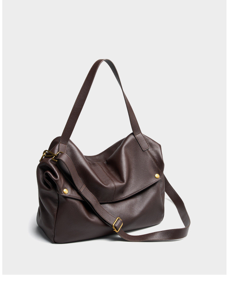 Angled side view of coffee brown leather tote with brass-tone hardware accents