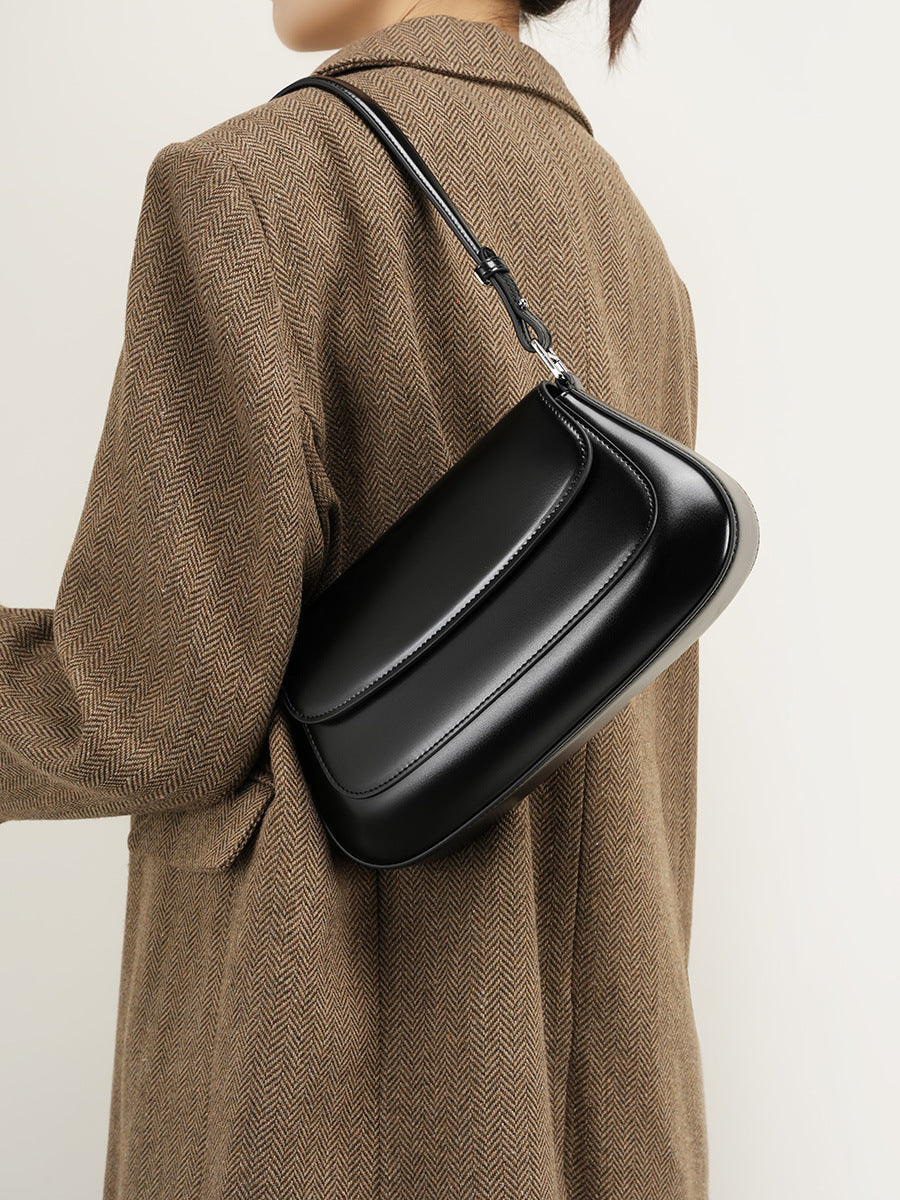 Model wearing the black leather baguette bag as a shoulder bag with a brown coat