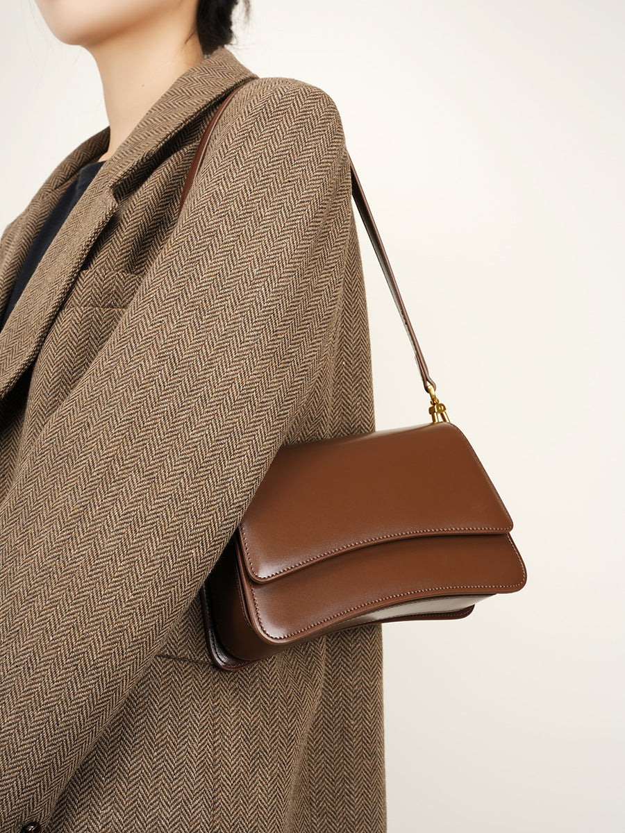 Side profile of brown leather baguette bag worn crossbody with autumn outfit