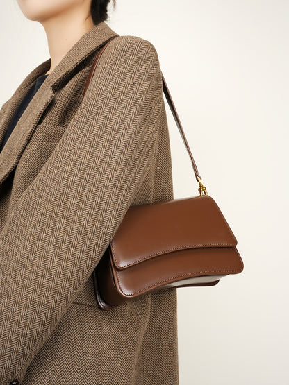 Side profile of brown leather baguette bag worn crossbody with autumn outfit