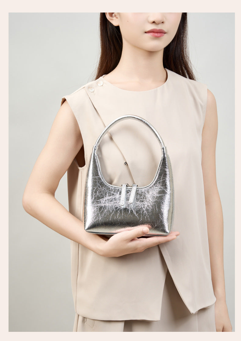 Model holding silver mini hobo bag in hand, front view